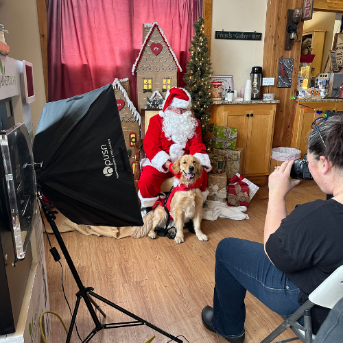 A photographer taking pictures with a dog and Santa Claus